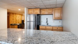 A kitchen with wooden cabinets, a stainless steel refrigerator, a granite countertop, and a tiled backsplash. - Ski-On/Off - private sauna - right next to lift - 1GB WiFi - Renovated (Killington)
