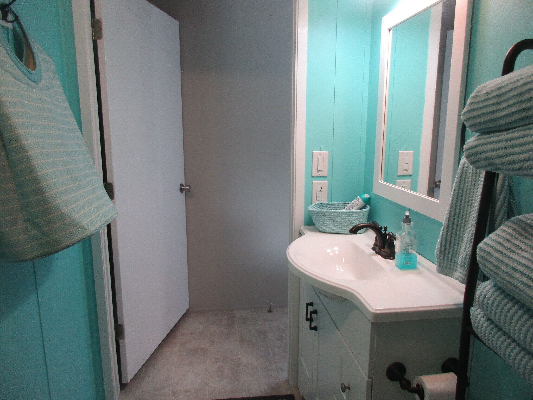 A bathroom with a white sink, a mirror, and a towel rack.