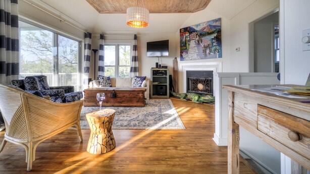 Amplia sala de estar con techo de madera, chimenea y ventanas grandes.