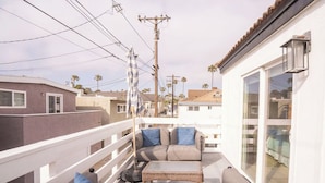 A balcony with outdoor furniture, a white railing, and a view of neighboring houses. - Beautiful 6bd/7bath steps to the sand (Newport Beach)