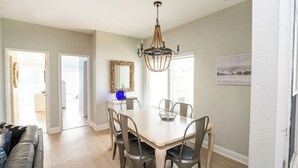 A dining area with a table and chairs, a chandelier, a mirror, and a painting on the wall. - Beautiful 6bd/7bath steps to the sand (Newport Beach)