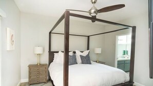 A four-poster bed with a ceiling fan, bedside tables with lamps, and a patterned rug. - Beautiful 6bd/7bath steps to the sand (Newport Beach)