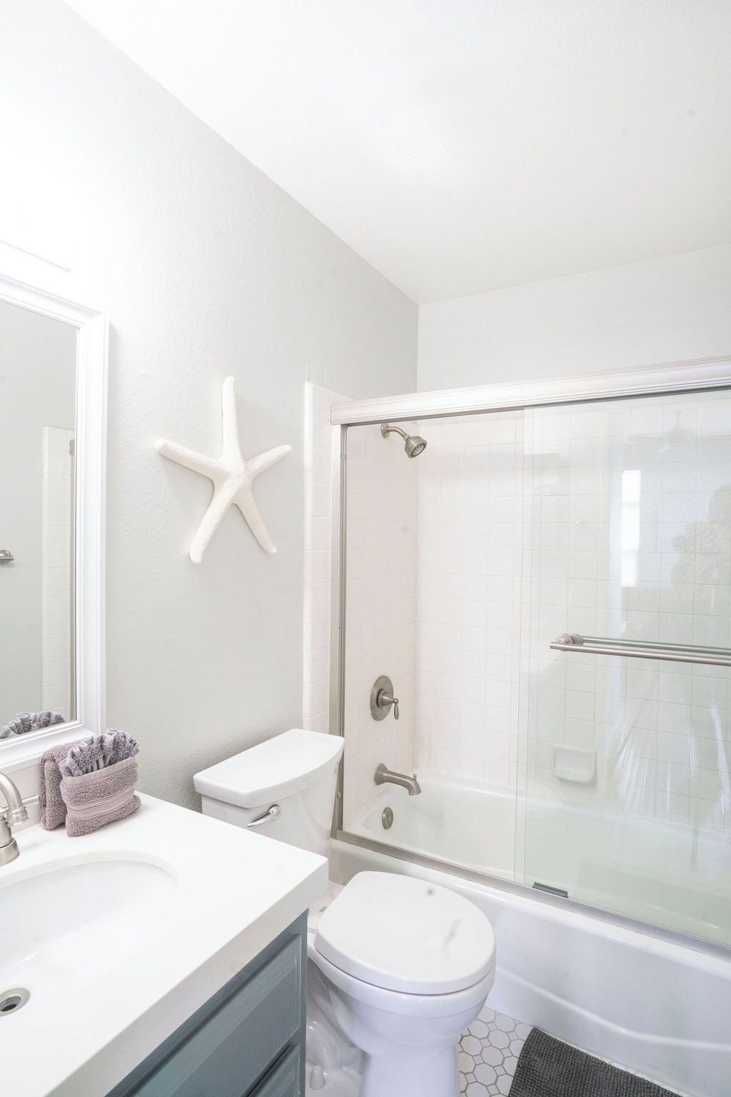 A bathroom with a white sink, toilet, and glass-enclosed shower.