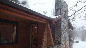 Una cabaña de troncos con fachada de piedra, una puerta de madera y una ventana.
