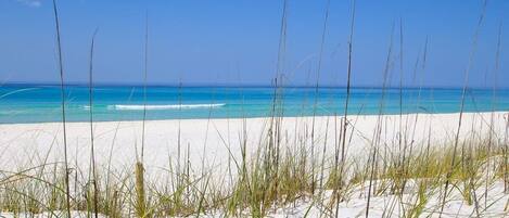 Une plage à l’eau turquoise et limpide et au sable blanc.