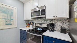 A kitchen with white cabinets, a microwave, a stove, and a coffee maker. - Steps To Beach Access, Pool, Tennis ~ Seaclusion at Cassine Gardens (Santa Rosa Beach)