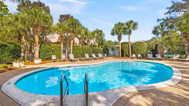 Une piscine avec des chaises longues et des palmiers.