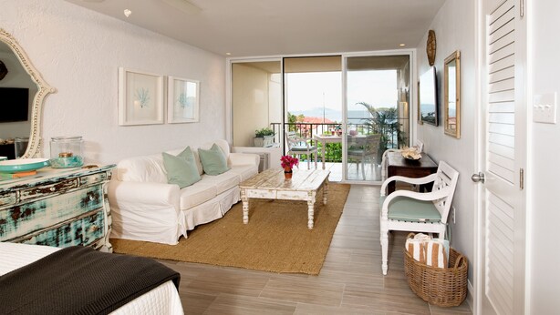 A spacious living room with a white sofa, a coffee table, and a view of the outdoors through a sliding glass door.