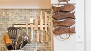 A kitchen with a tiled backsplash, a spice rack, and various utensils.