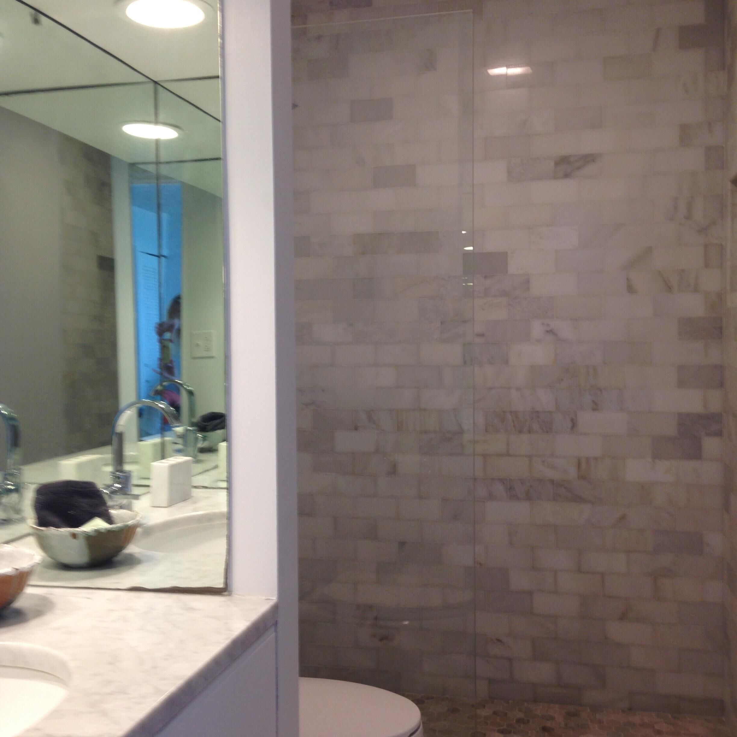 Ein Badezimmer mit Duschkabine aus Glas, Waschbecken mit Spiegel und Toilette.