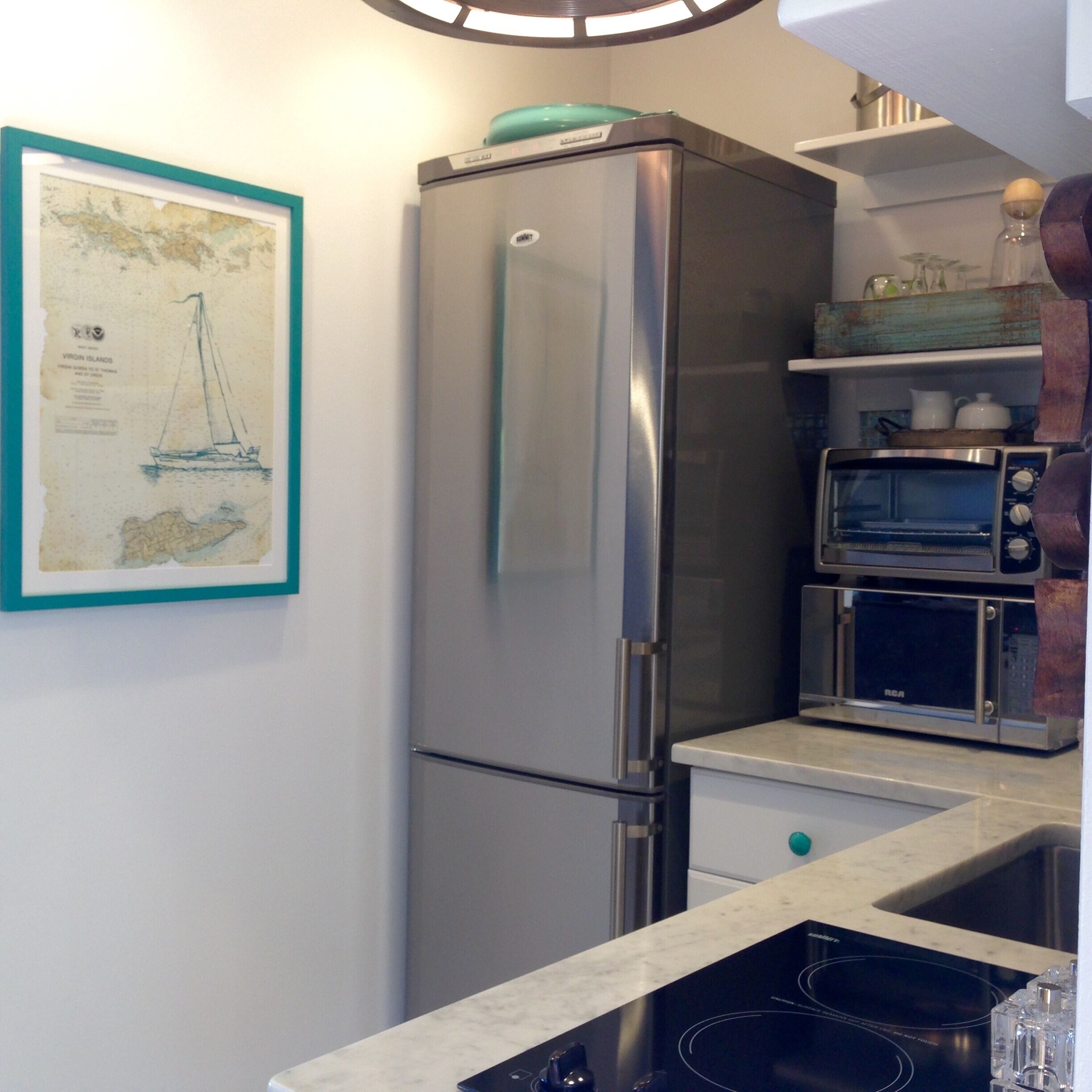 A kitchen with a stainless steel refrigerator, a built-in oven, and a microwave.