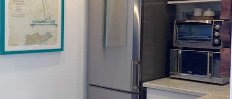 Uma cozinha com geladeira de aço inoxidável, forno embutido e micro-ondas.