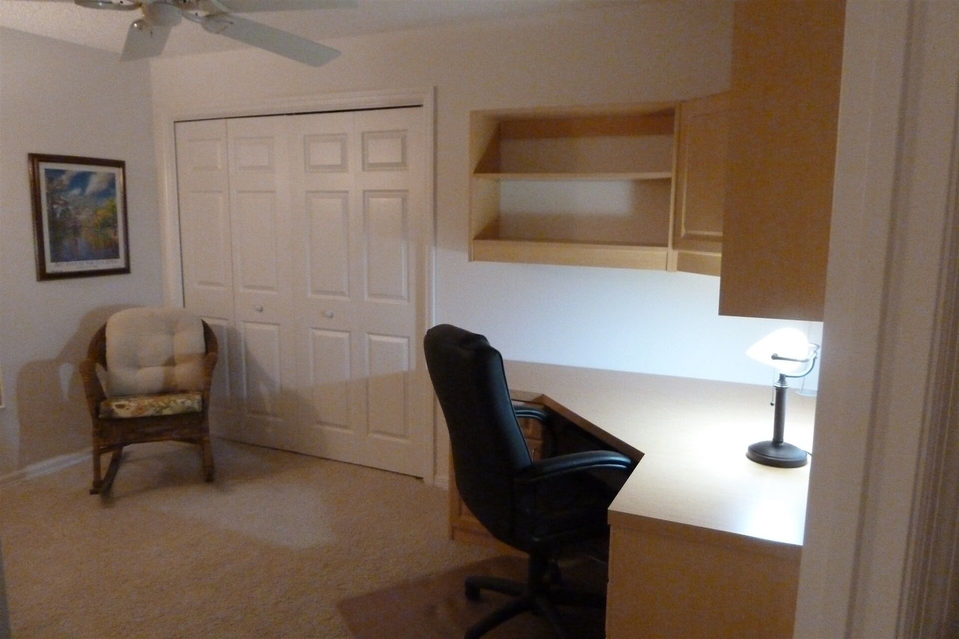 A room with a closed door, a chair, a desk, and a lamp.