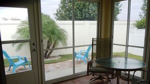 A patio with a glass door, a round table, and blue chairs. - Charming 3/2 Virginia Trace Villa, next to Lake Sumter Landing, with golf cart (The Villages)