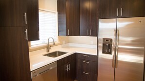 Una cucina moderna con pensili in legno scuro, elettrodomestici in acciaio inossidabile e un dispenser di acqua integrato.
