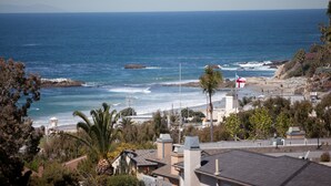 Panorama costiero con spiaggia, costa rocciosa e edifici residenziali.