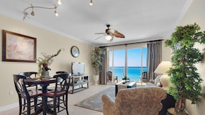 A living room with a dining area, a ceiling fan, a large window with a view of the ocean, and a potted plant. - Beachfront Condo!Beautiful View, On the Beach! Unit 308 (Destin)