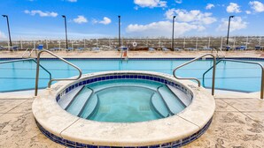 Une piscine avec un jacuzzi, entourée de chaises longues et d’une clôture.