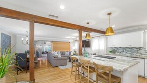 A modern kitchen with wooden beams, a marble island, and a dining area with a sofa and chairs.