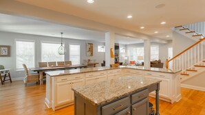 A spacious kitchen with a central island, white cabinetry, and a wooden staircase. - Spacious Rehoboth/Dewey Beach House Sleeps 17 (Rehoboth Beach)