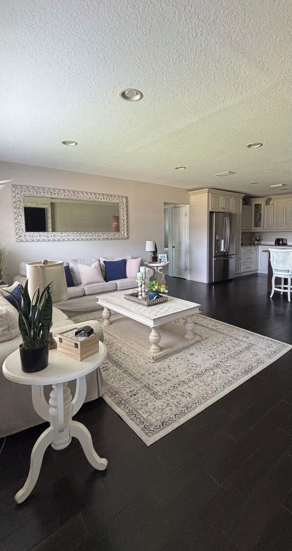 A modern living room with a sofa, coffee table, and a dining area with a chair.