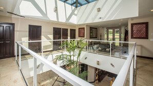 Un intérieur spacieux doté d’une verrière, de nombreuses portes et d’un escalier central.