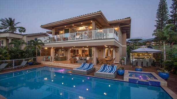 Une maison à deux étages avec une piscine, un espace salon extérieur et une terrasse couverte.