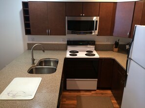 A compact kitchen with a stainless steel sink, a microwave, a stove, and a refrigerator.