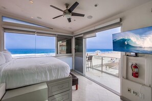 A bedroom with a bed, a ceiling fan, a TV, and a balcony with a view of the ocean. - 2 Story + Ocean Front + AC + Exclusive View Balcony (San Diego)