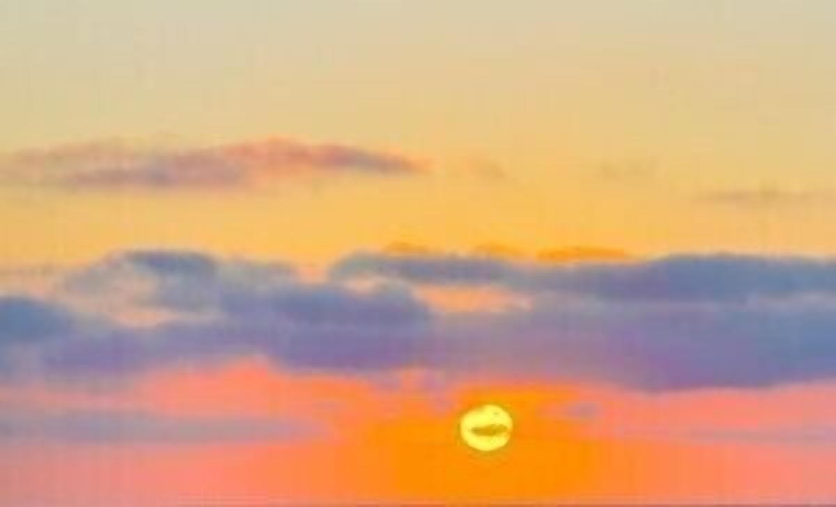 A sunset with clouds and a visible sun.