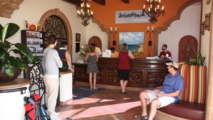 A reception area with a wooden counter, a chandelier, and a mural on the wall. - Ground Floor, Oceanview And Oceanfront  (San Jose del Cabo)