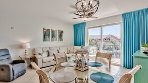 A modern living room with a glass coffee table, beige sofa, blue armchair, and a green cabinet. - Relax and Enjoy Gulf Views & Excellent Pools, 3rd floor, Garage Parking (Miramar Beach)