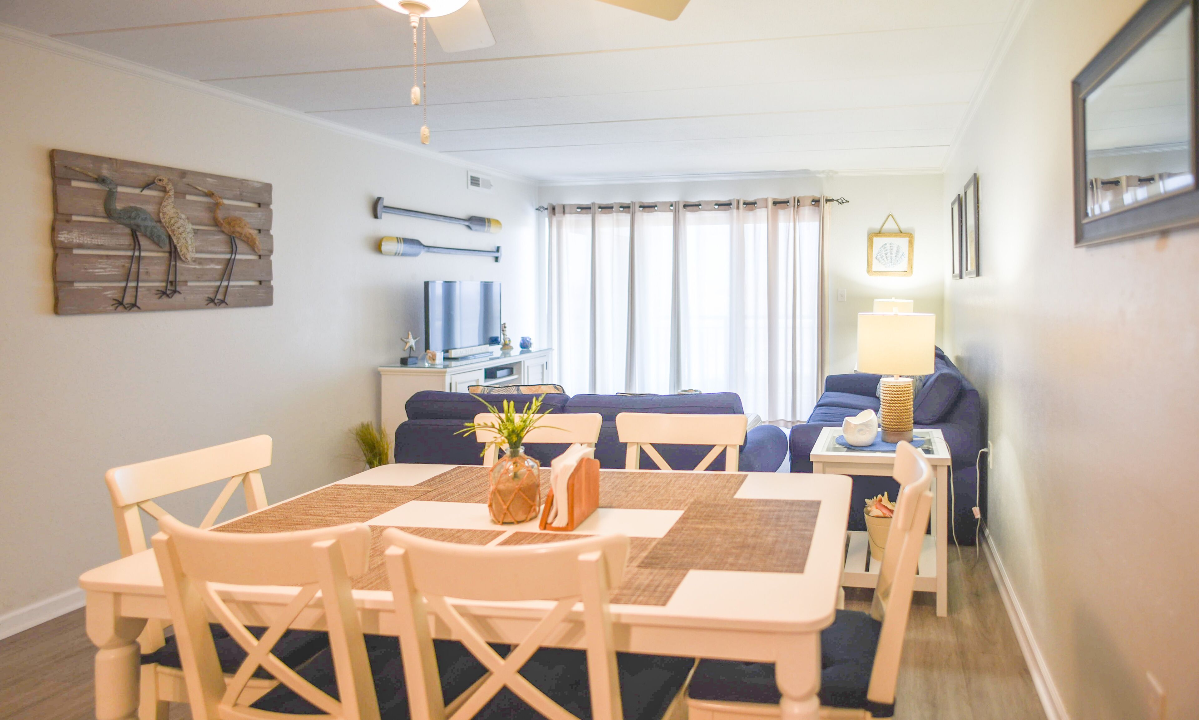 A dining area with a table and chairs, a sofa, and a TV in the background.