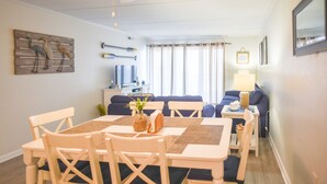 A dining area with a table and chairs, a sofa, and a TV in the background. - Direct Oceanfront, Mid-Town, Updated & Spacious 1st Floor - Walk off to Beach (Ocean City)