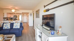 A living room with a TV, a sofa, and a dining area in the background. - Direct Oceanfront, Mid-Town, Updated & Spacious 1st Floor - Walk off to Beach (Ocean City)