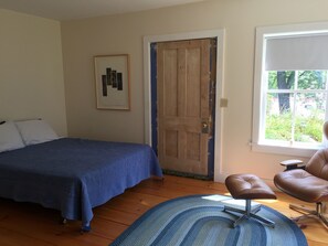 A bedroom with a bed, a chair, a door, and a window. - In town, river across the street, families welcome (Waitsfield)