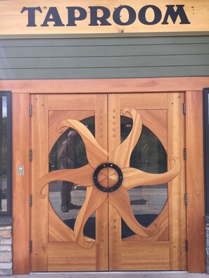 A wooden door with a circular design and the word 'TAPROOM' above it.