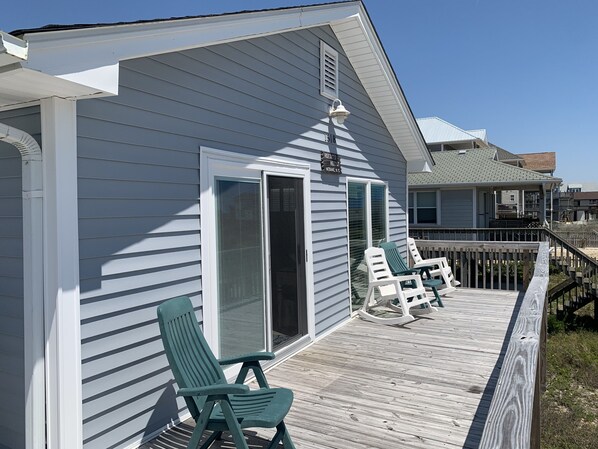 A house with a covered porch, two green chairs, and a white fence.