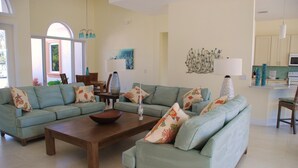 A spacious living room with a large L-shaped sofa set, a wooden coffee table, and a dining area with a table and chairs. -  Beautiful Home in Key Colony Beach! Private Pool. Dock. Tiki Hut (Key Colony Beach)