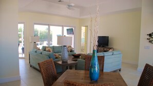 A living room with a dining table, wicker chairs, a sofa, and a television. -  Beautiful Home in Key Colony Beach! Private Pool. Dock. Tiki Hut (Key Colony Beach)