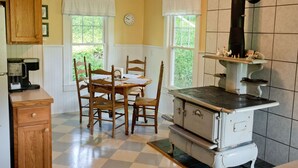 Une cuisine équipée d’une cuisinière, de chaises en bois, d’une table à manger et d’une horloge au mur.