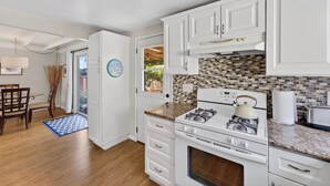 Una cocina con armarios blancos, estufa a gas y salpicadero de azulejos.