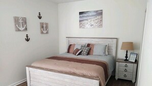 A bedroom with a bed, a nightstand, a lamp, and wall decorations.
