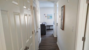 A hallway with white doors, a bench, and artwork on the walls.