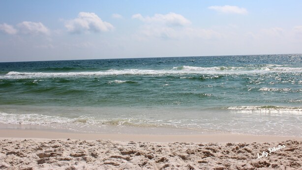 A beach with waves and a clear sky.