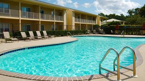 A swimming pool with lounge chairs and a building with balconies in the background.