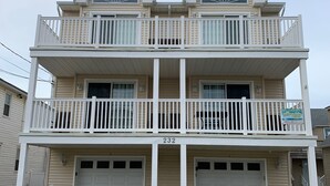 Une maison à deux étages avec un balcon, un garage et des fondations en pierre.