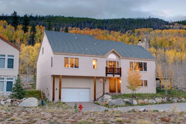 A two-story house with a garage, a balcony, and a driveway leading to a red fire hydrant.