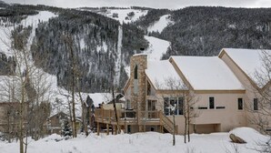 A lodge with a stone chimney, wooden deck, and a view of snow-covered mountains. - 5BR+Loft BR Home in Keystone Ski Area-pvt. hot tub; great view; 16 separate beds (Keystone)