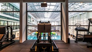 Academia com vista para uma piscina interior através de grandes janelas.